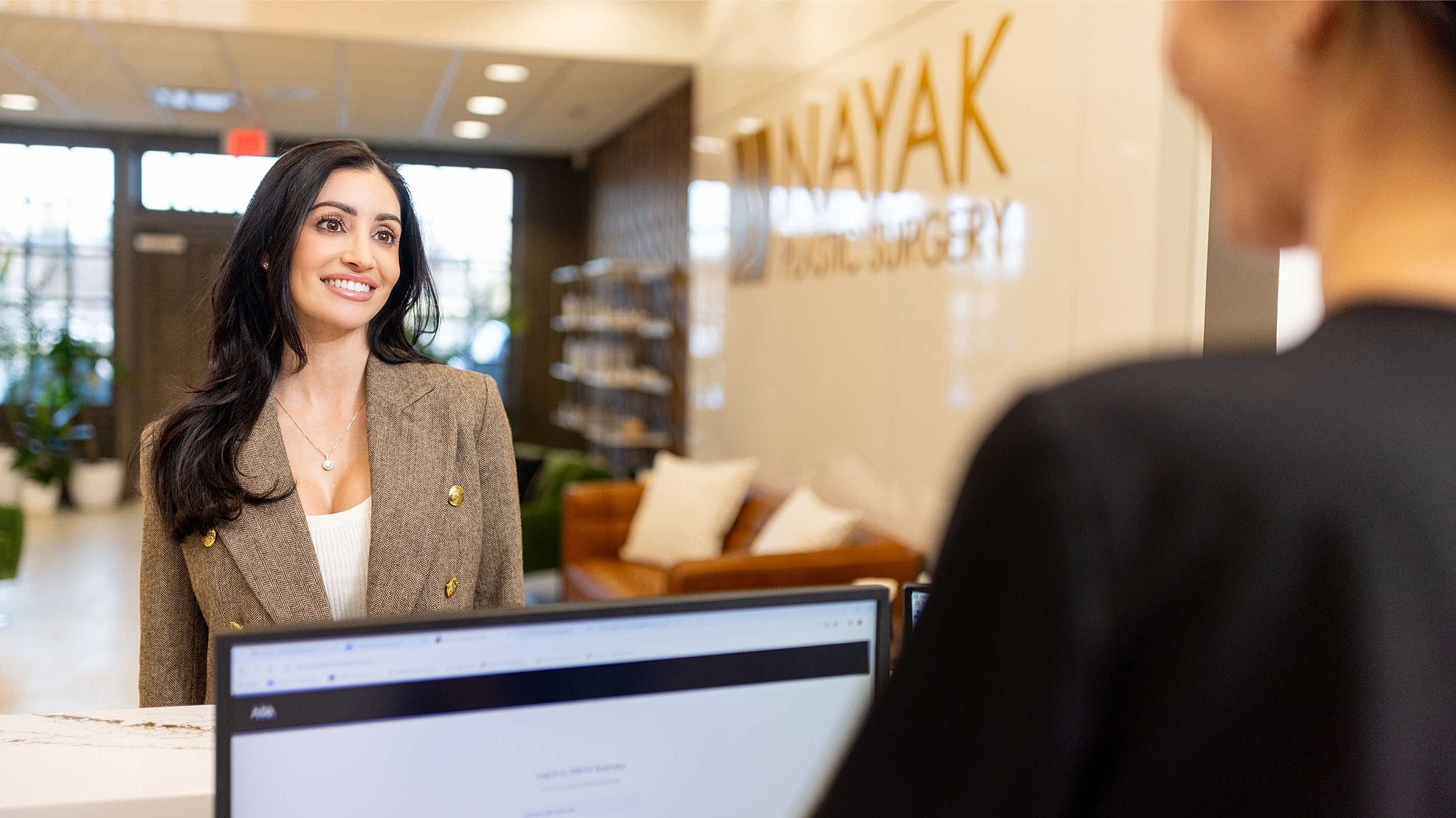 St. Louis Dermaplaning model smiling at reception in medical office.