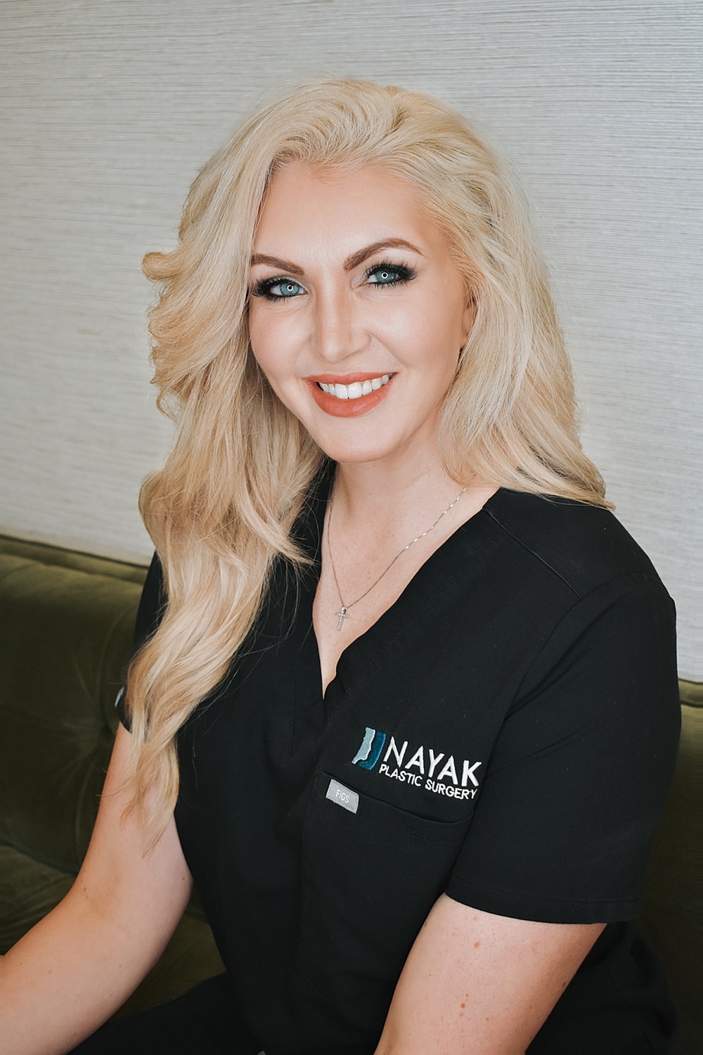 Smiling woman in medical attire at clinic.