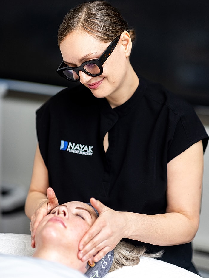 Skincare professional performing facial treatment on client.