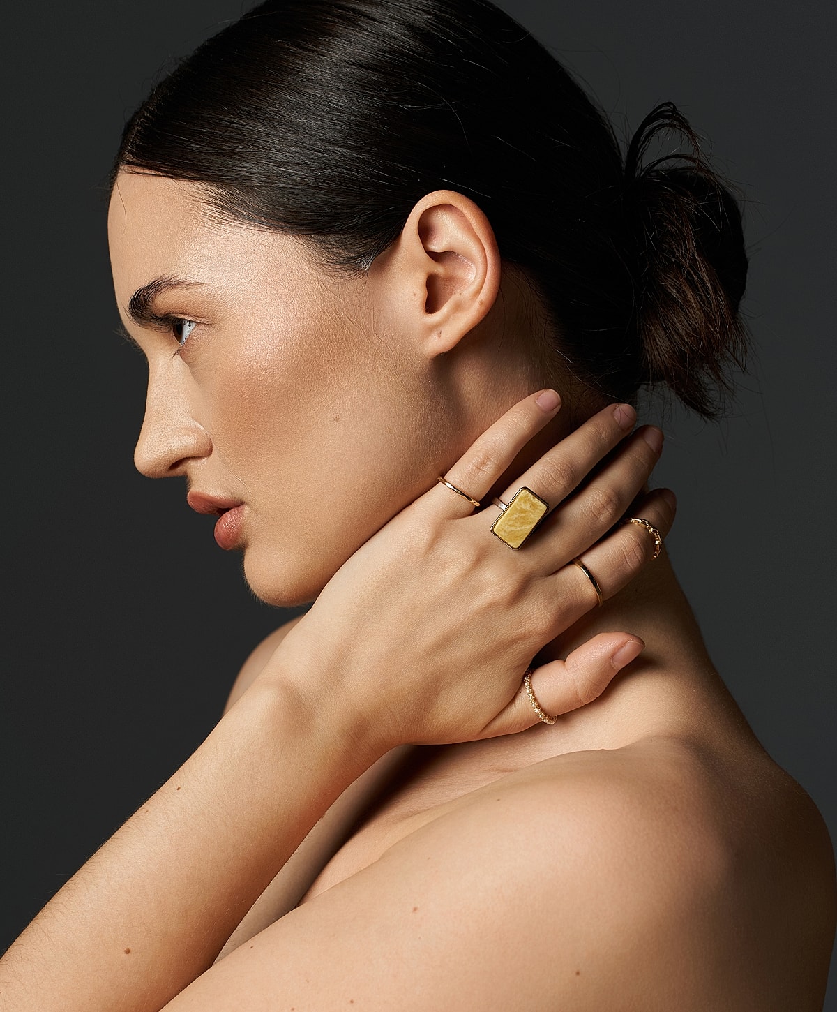 Model showcasing elegant jewelry on dark background.