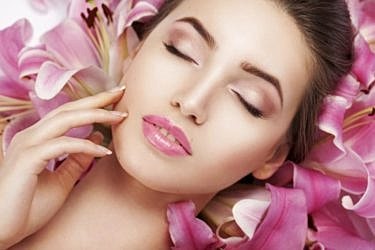 St. Louis VBeam Laser Treatment model surrounded by pink lilies, serene expression.