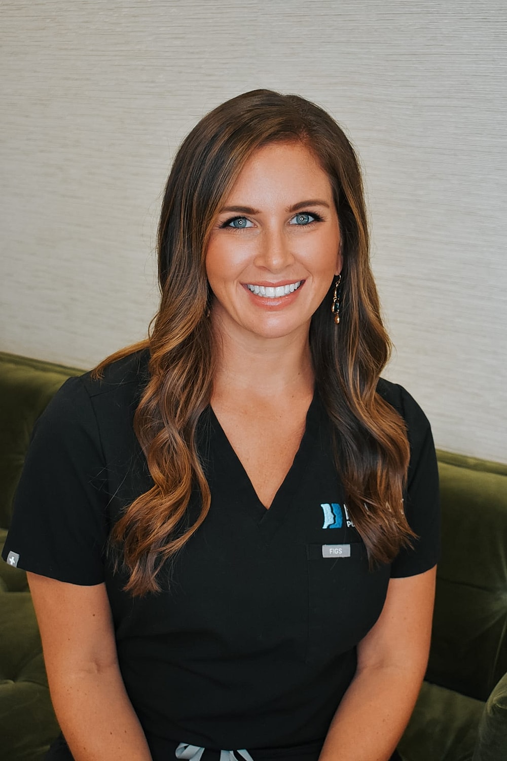 Smiling woman in scrubs sitting on a sofa.