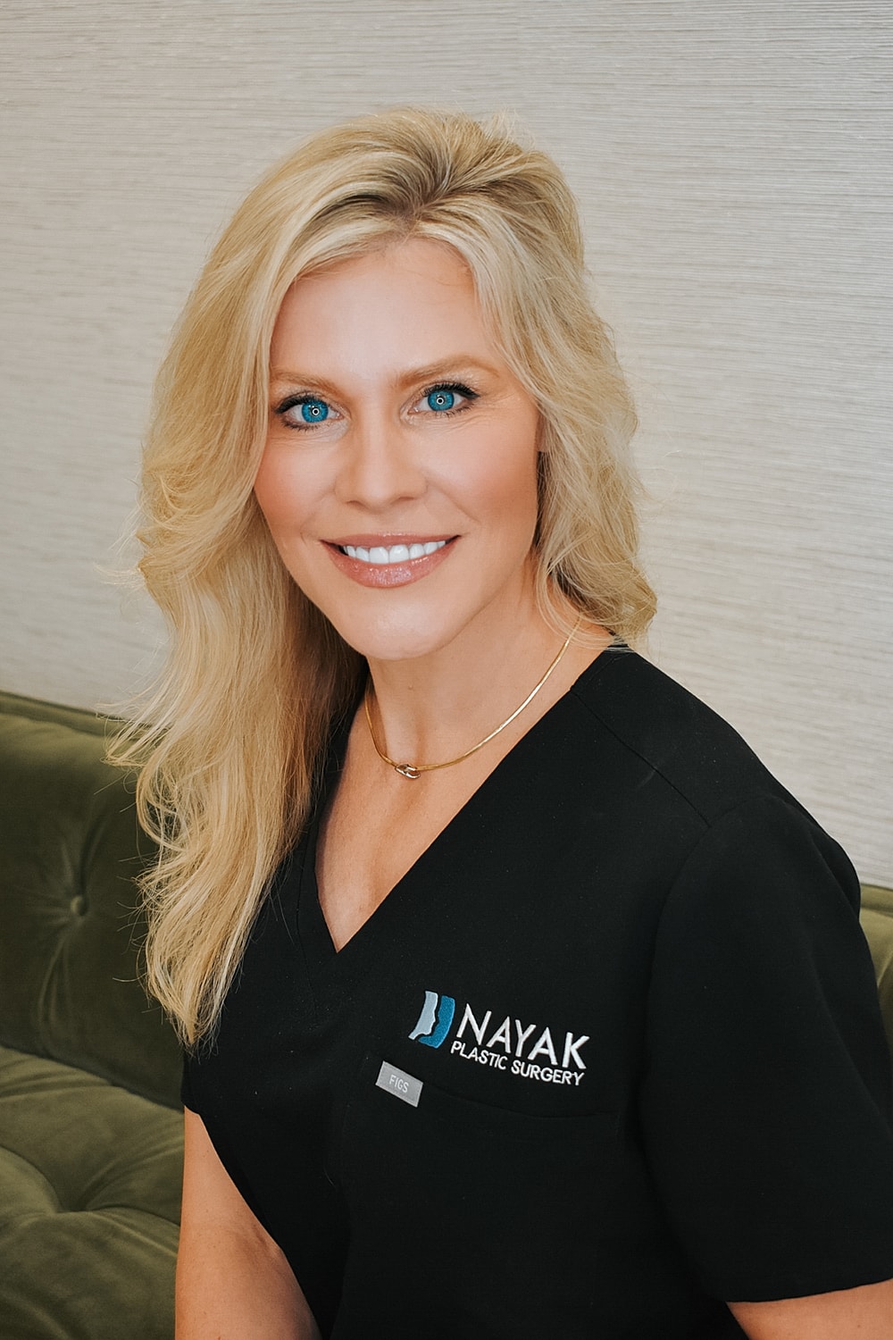 Smiling woman in medical attire, professional setting.