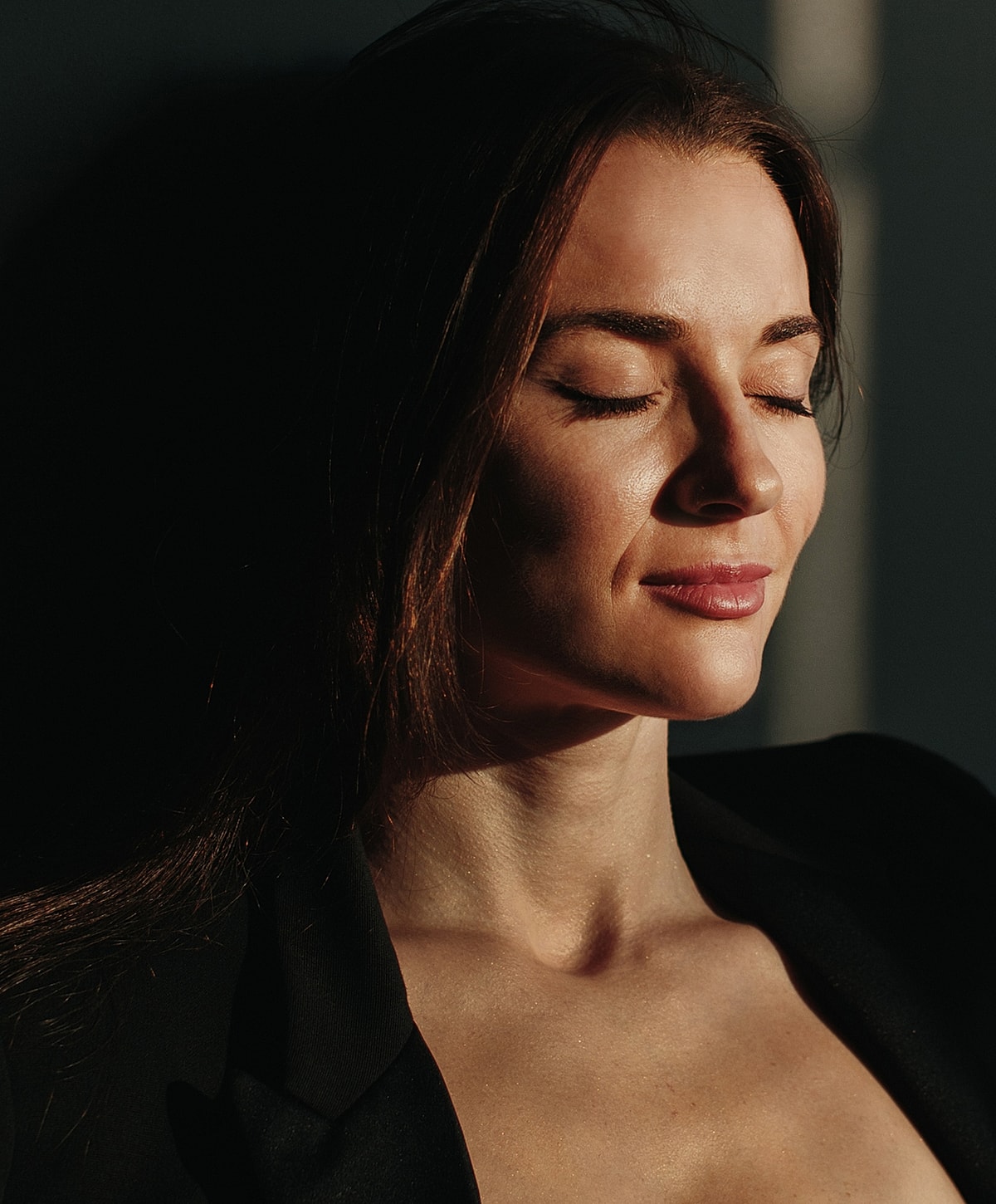 Woman with closed eyes in soft sunlight.