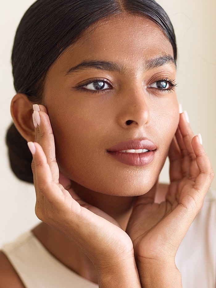 Woman gently touching her face with a smile.