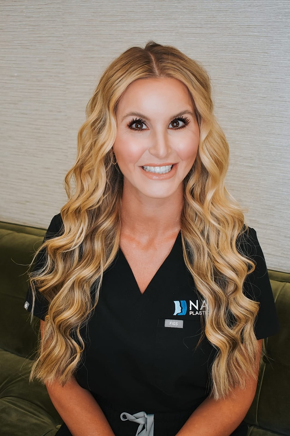 Smiling woman in black scrubs with curly hair.