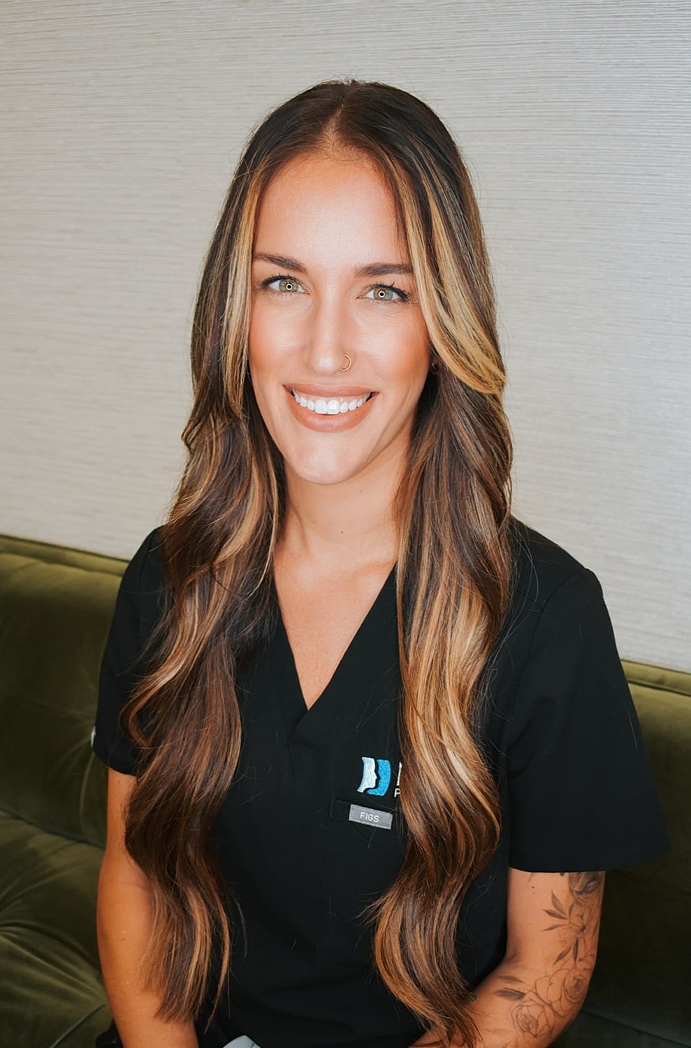 Smiling woman in medical scrubs, long hair.
