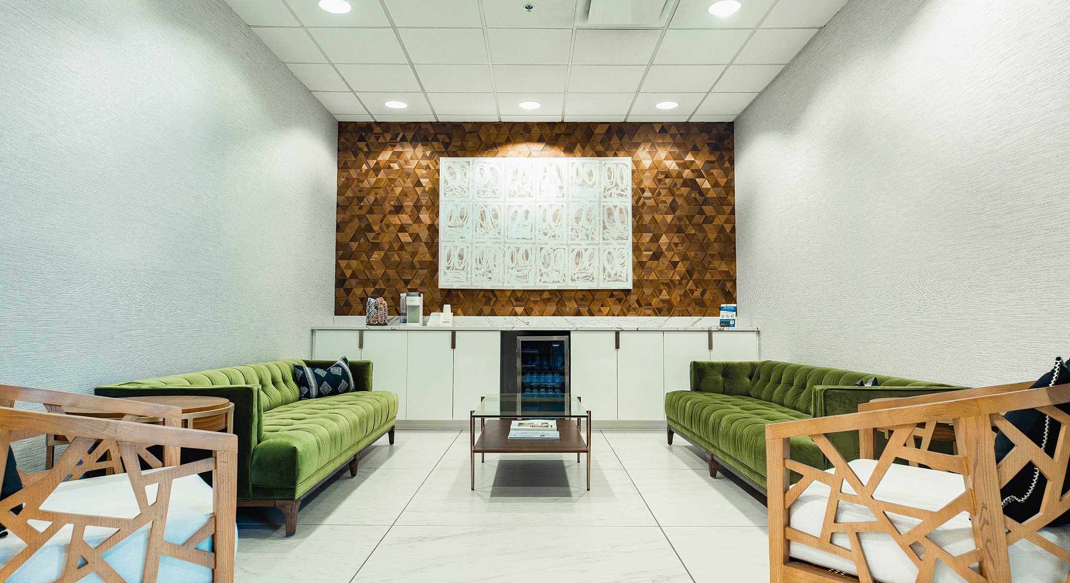 Modern waiting area with green sofas and decor.